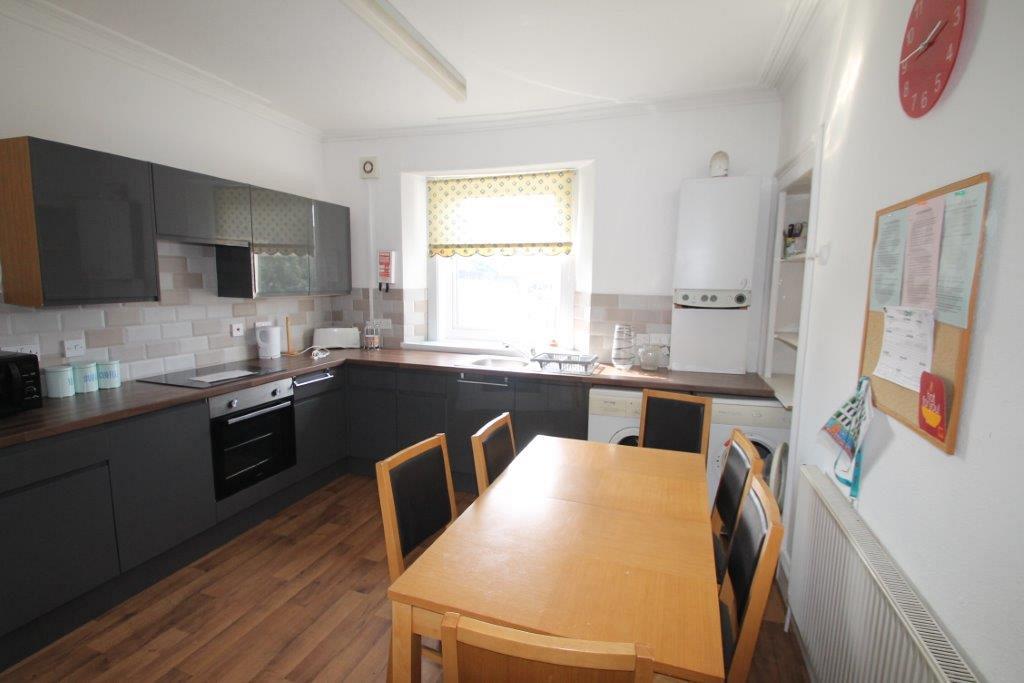 kitchen with induction hobs and cooker, washing machine and tumble dryer and dining table with six dining chairs
