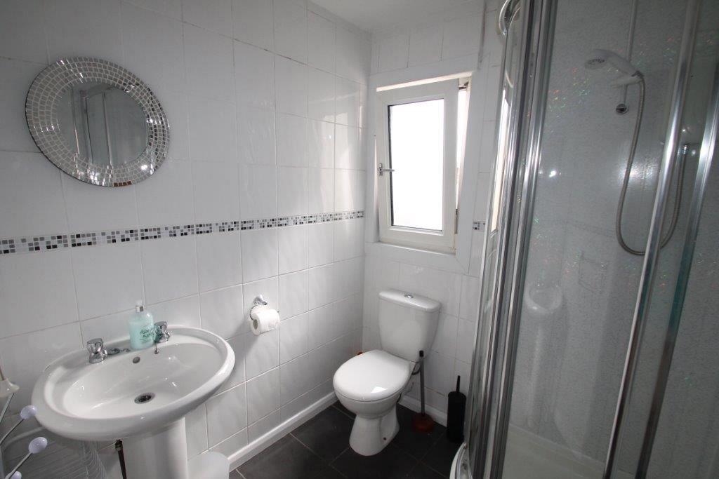 Second shared bathroom with corner shower and circular mirror on wall above sink