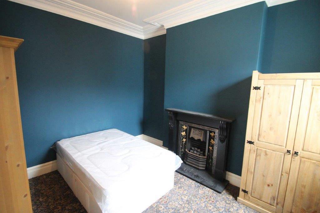 Blue walled student room with doubled bed, x2 two door wardrobe and black feature fireplace