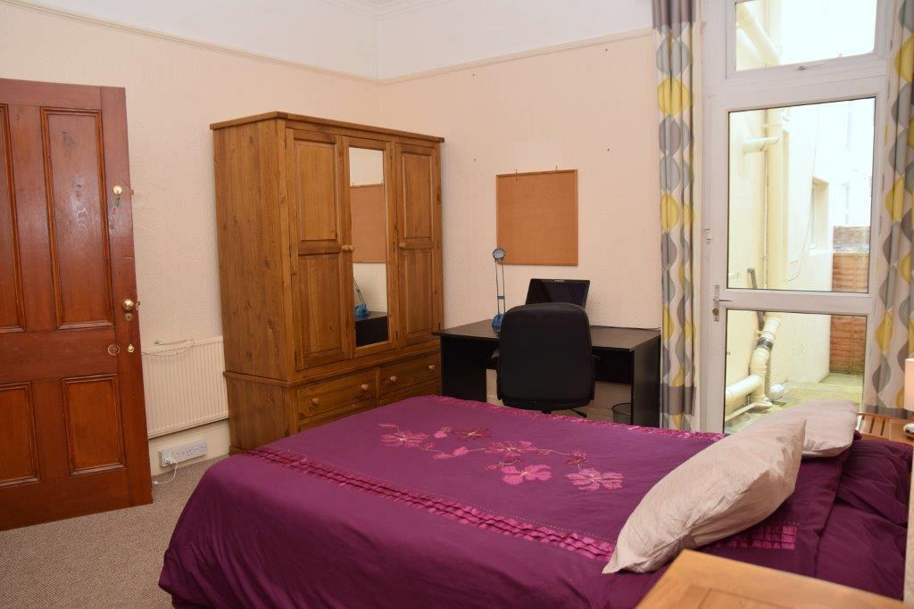 Third student bedroom with double bed, three door wardrobe, chest of drawers, desk and two pin boards on walls