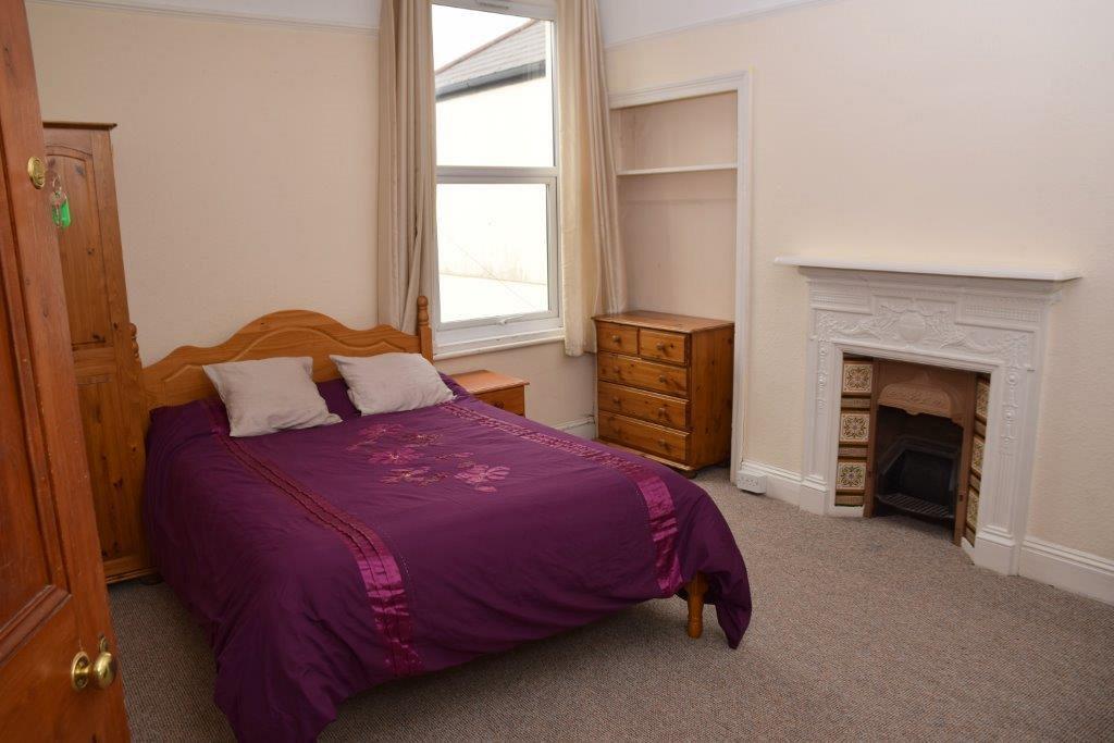 Fourth student bedroom with double bed, chest of drawers, two door wardrobe, large window and fire place