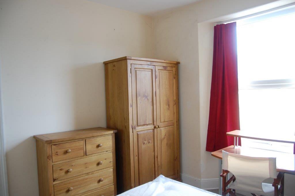 Third student bedroom with double bed, desk in front of window, chest of drawers and two door wardrobe