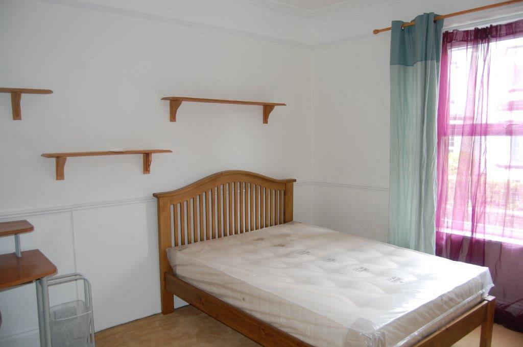 Fourth student bedroom with double bed, desk and three shelves above bed