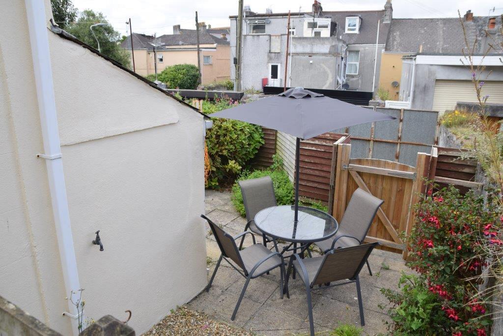 Shared back patio with outside furniture and gate leading to back street