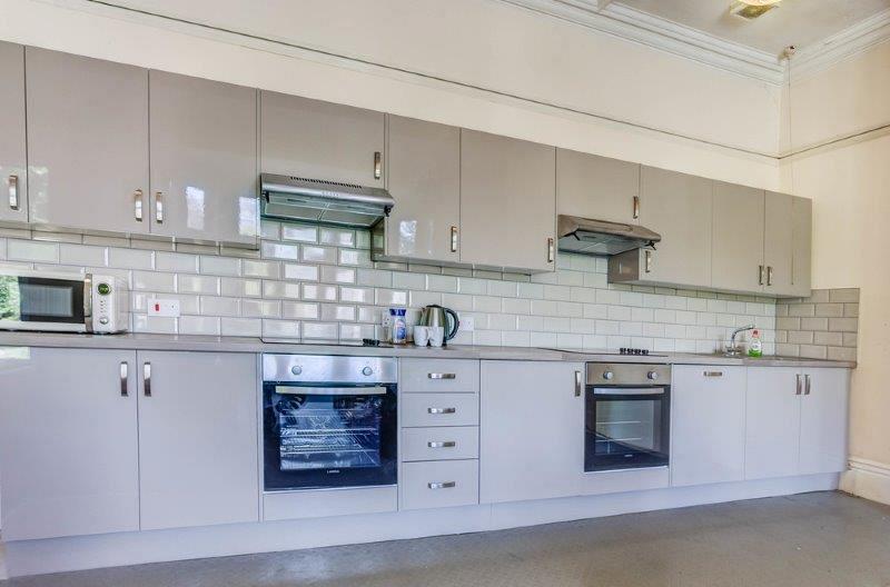 Grey kitchen with two cookers with induction hobs, dishwasher, washing machine, microwave 