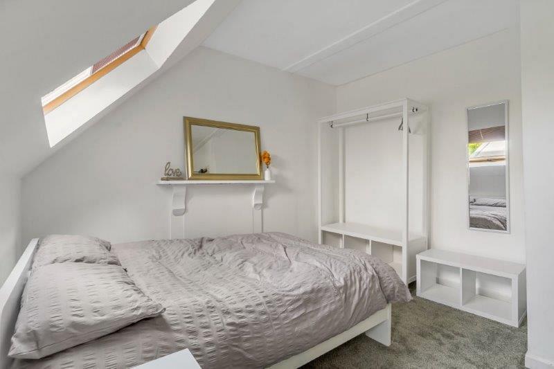 student bedroom with double bed, white clothing rail with underneath storage, bedside table, small shelving unit and full length mirror