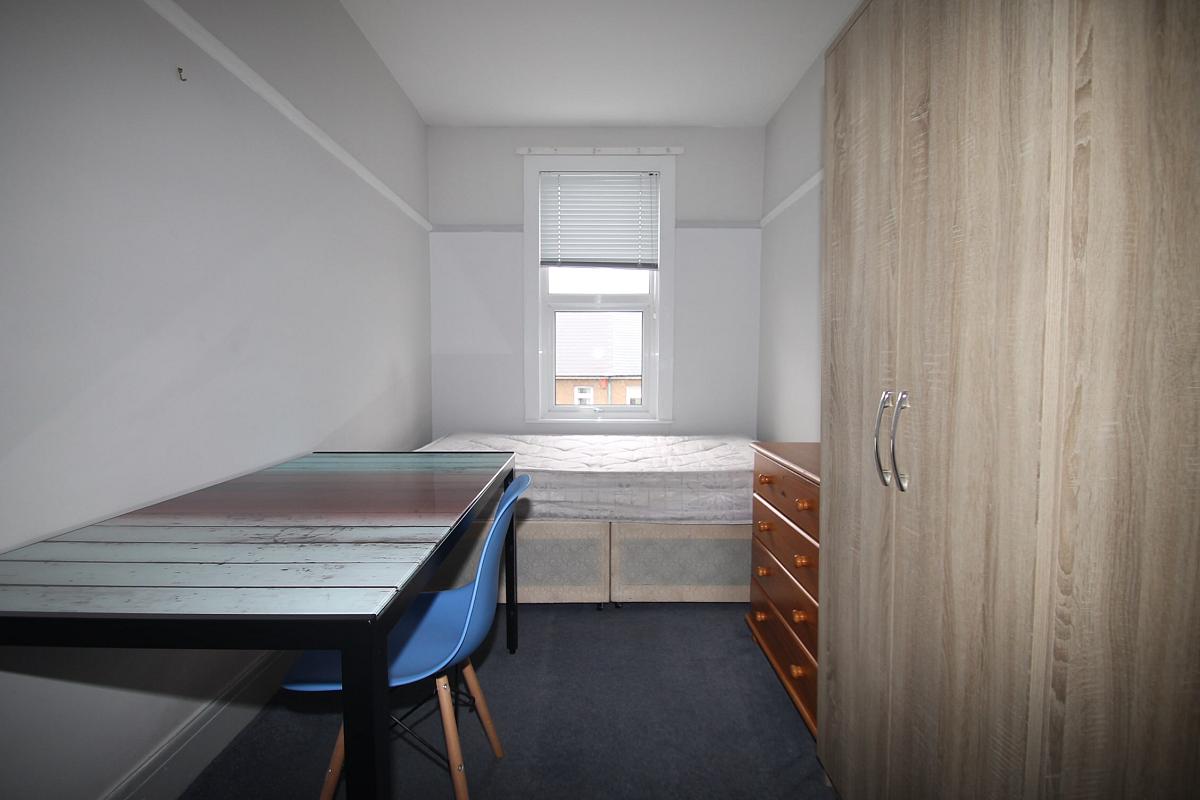 Student bedroom with double bed, two door wardrobe, chest of drawers and desk with blue chair