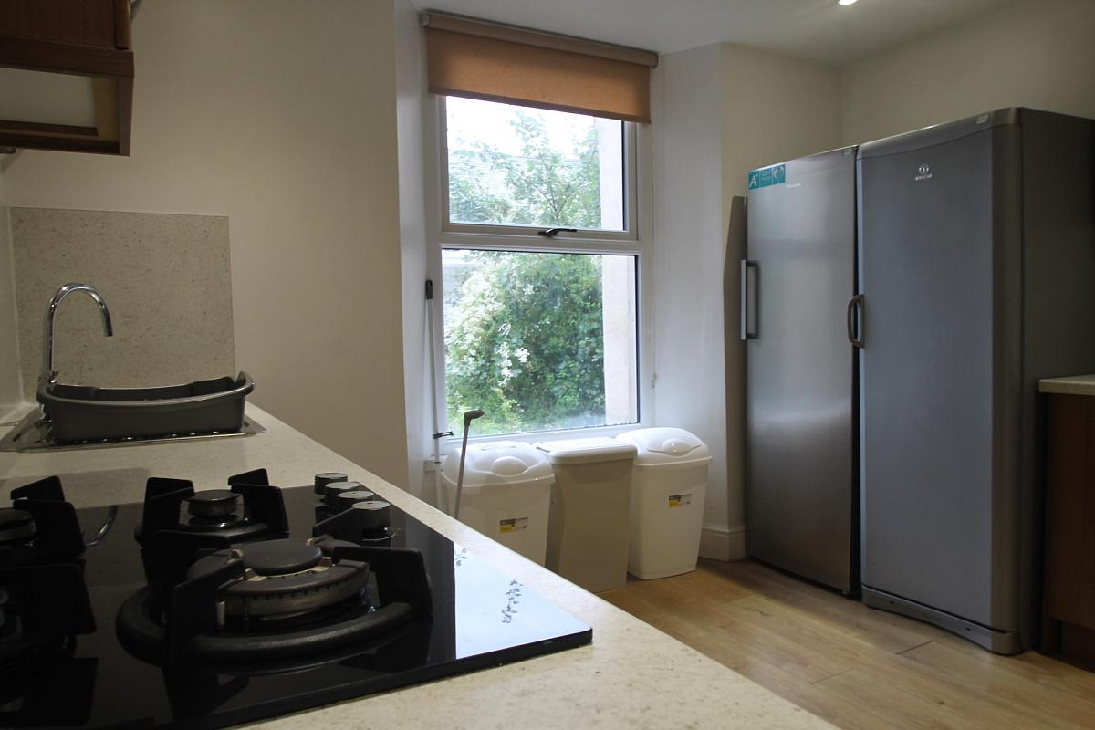 shared kitchen with gas hobs and cooker, two fridge freezers and three bins