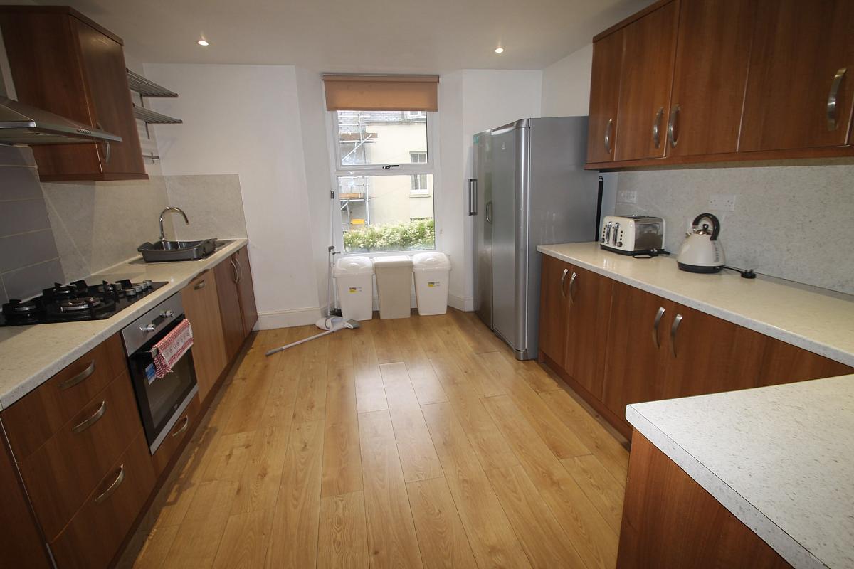 Large shared kitchen with two fridge freezers, gas hob and cooker, three bins and sink