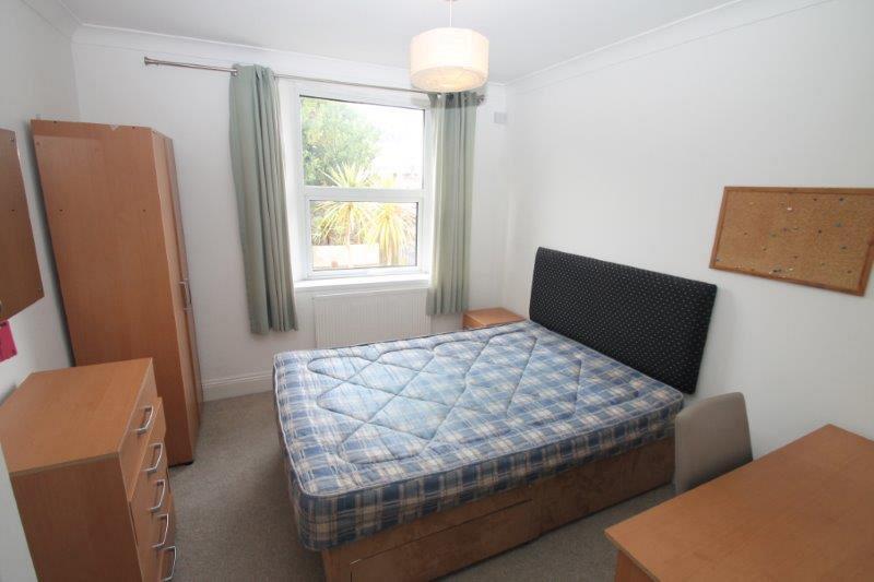 Student bedroom with double bed, two door wardrobe, chest of drawers, desk with chair, bedside table and pinboard on wall