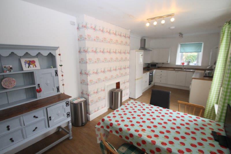 Dining area with dining table with four dining chairs, blue shelving unit, leading to open kitchen