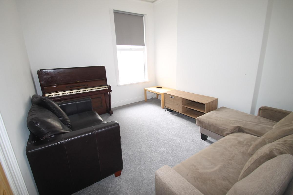 shared living room with two double sofas and piano