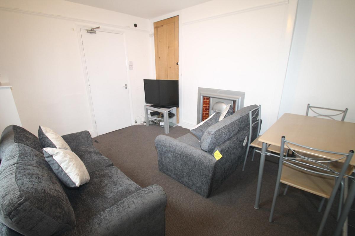 living space with two grey two-seater sofas, tv on tv stand and dining table with four dining chairs