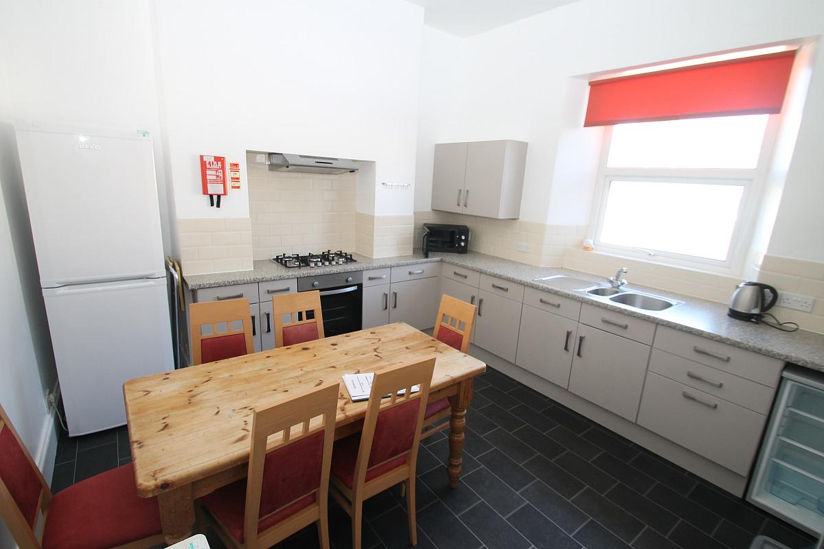 Shared kitchen with fridge freezer, small freezer, hob and cooker and dining table