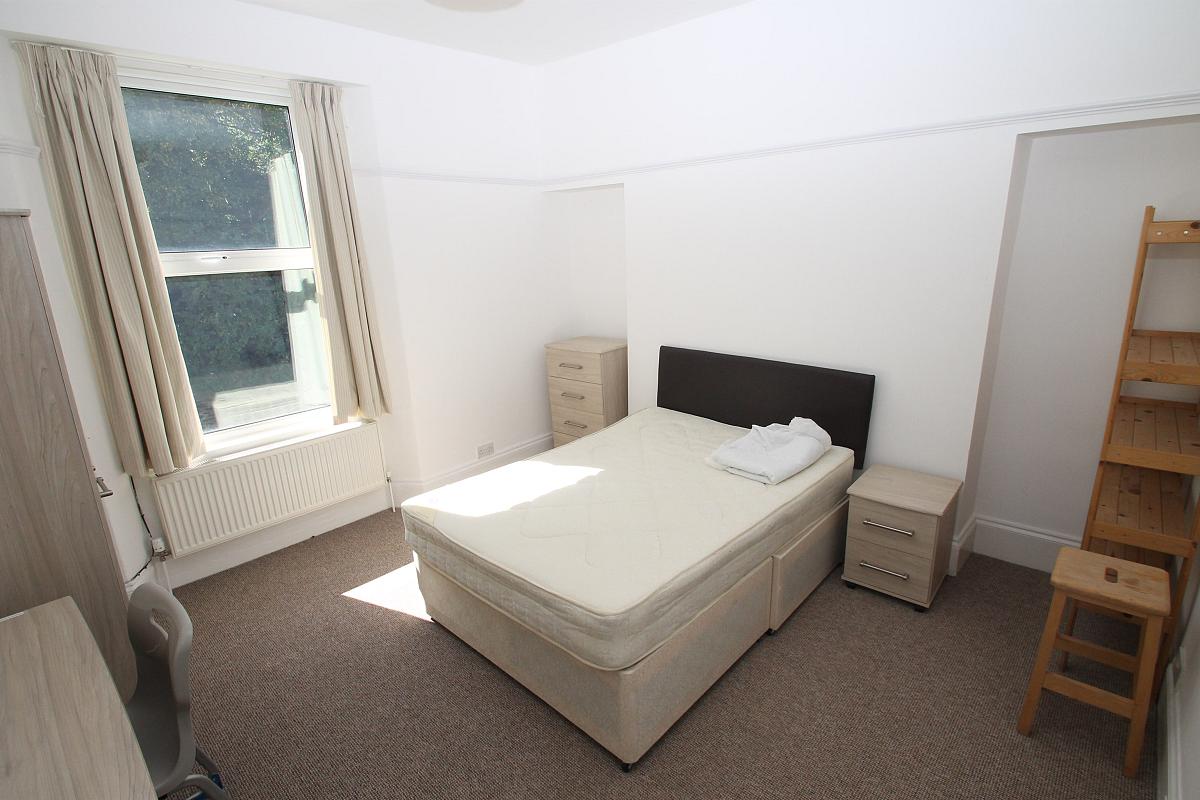 Fourth student bedroom with double bed, two door cupboard, shelving unit, chest of drawers and desk