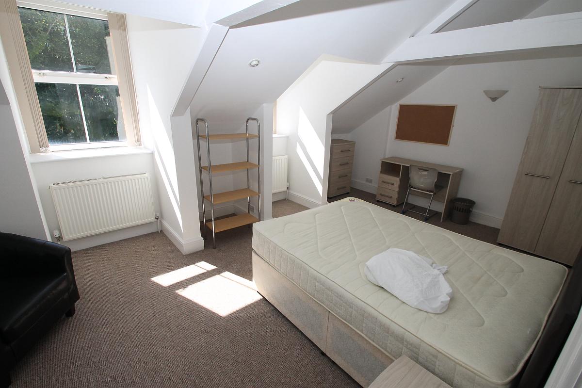 First student bedroom with double bed, two door wardrobe, desk, chest of drawers, shelving unit and arm chair