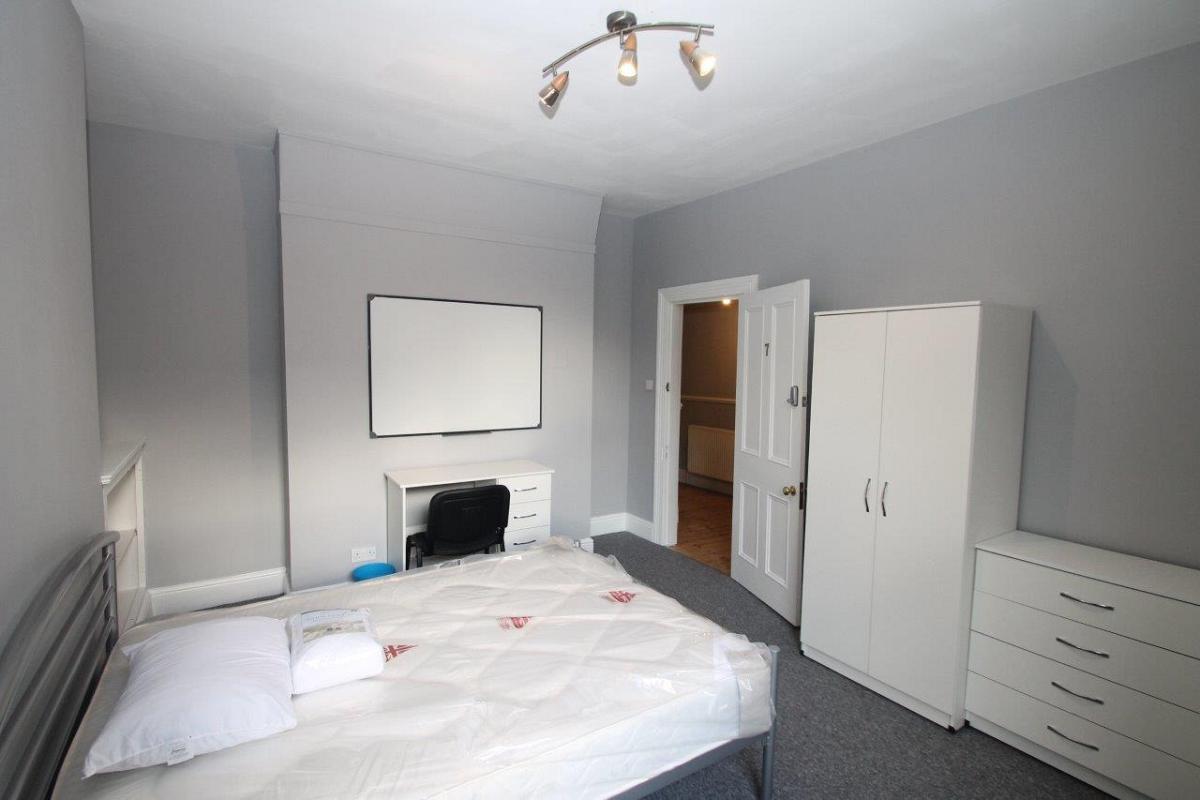 Seventh student bedroom with double bed, two door wardrobe, chest of drawers, desk, whiteboard and in wall shelving unit