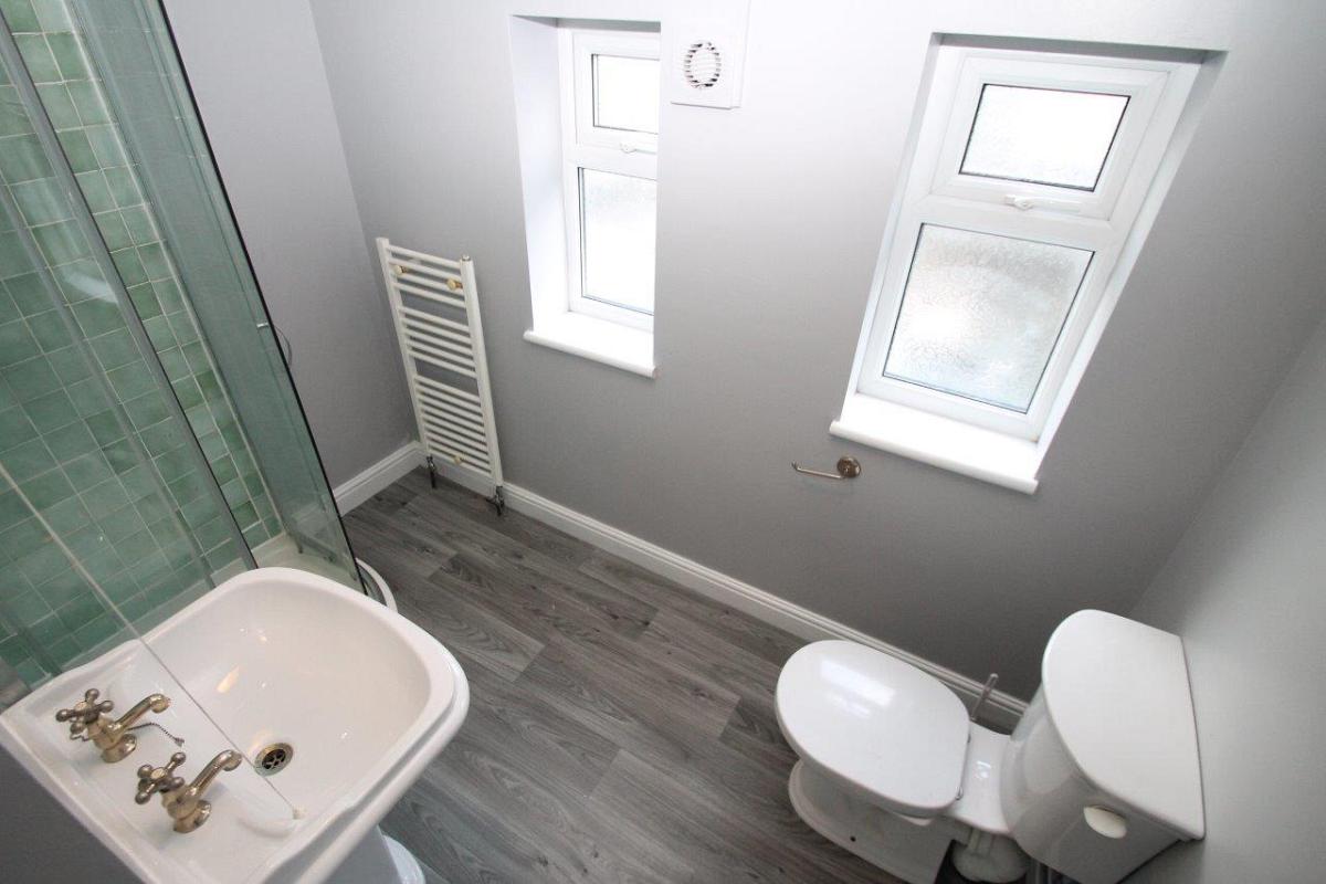 Shared bathroom with green tiled shower