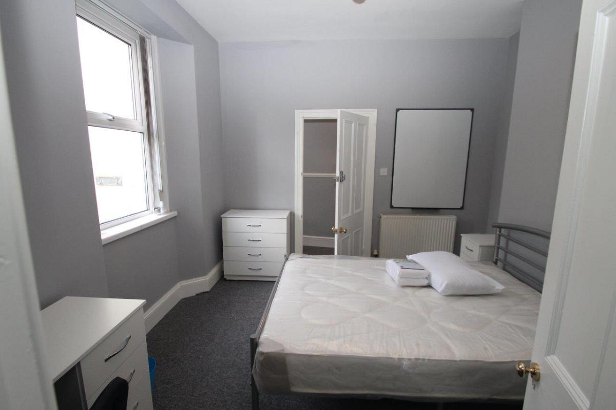Student bedroom with double bed, chest of drawers, desk and whiteboard