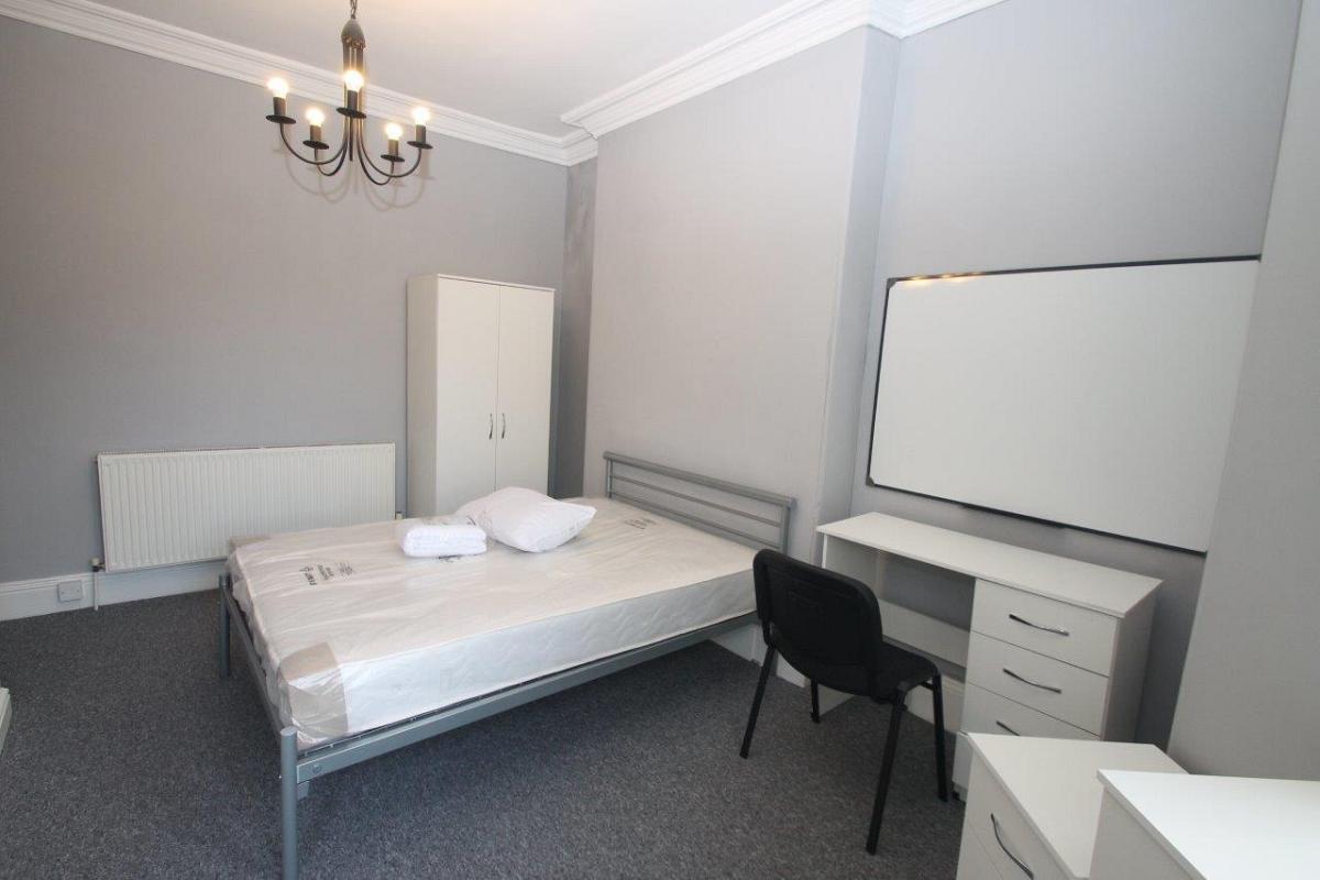 Student bedroom with double bed, chest of drawers, bedside table, two door wardrobe, desk and whiteboard