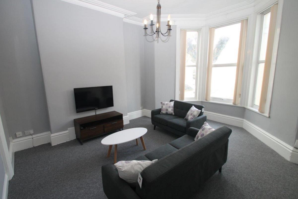 Spacious living room with a two seater sofa, three seater sofa, tv and large bay window