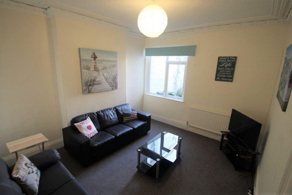 living room with black leather three-seater sofa, black two-seater sofa, glass coffee table and tv on tv stand