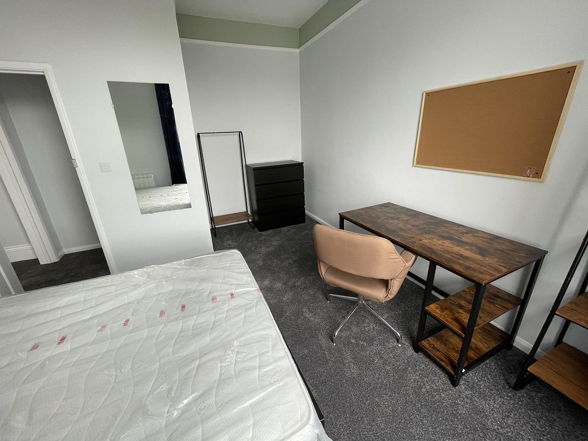 Student bedroom with double bed, chest of drawers, clothes rail and desk