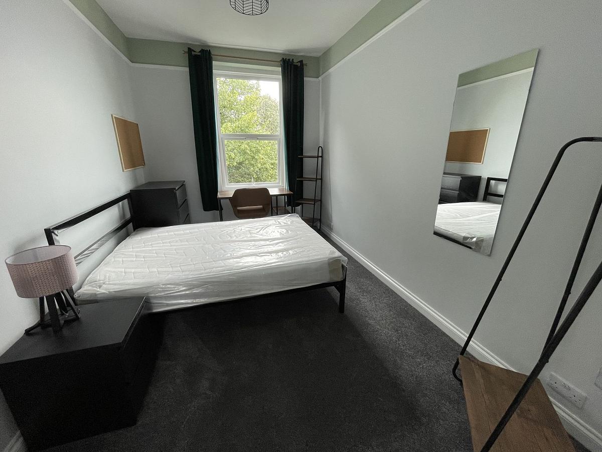 Student bedroom with double bed, chest of drawers, clothes rail and full length mirror