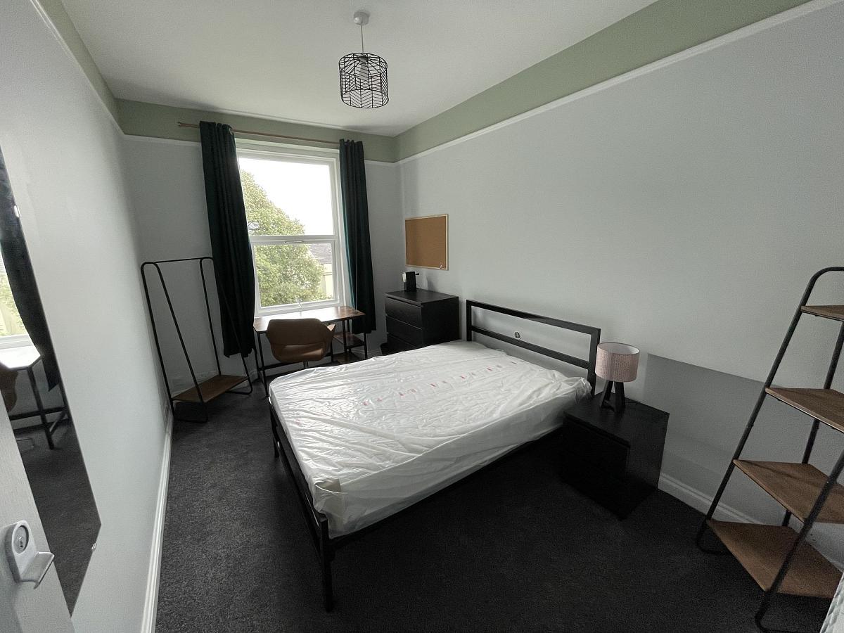 Student bedroom with double bed, chest of drawers, clothes rail and desk