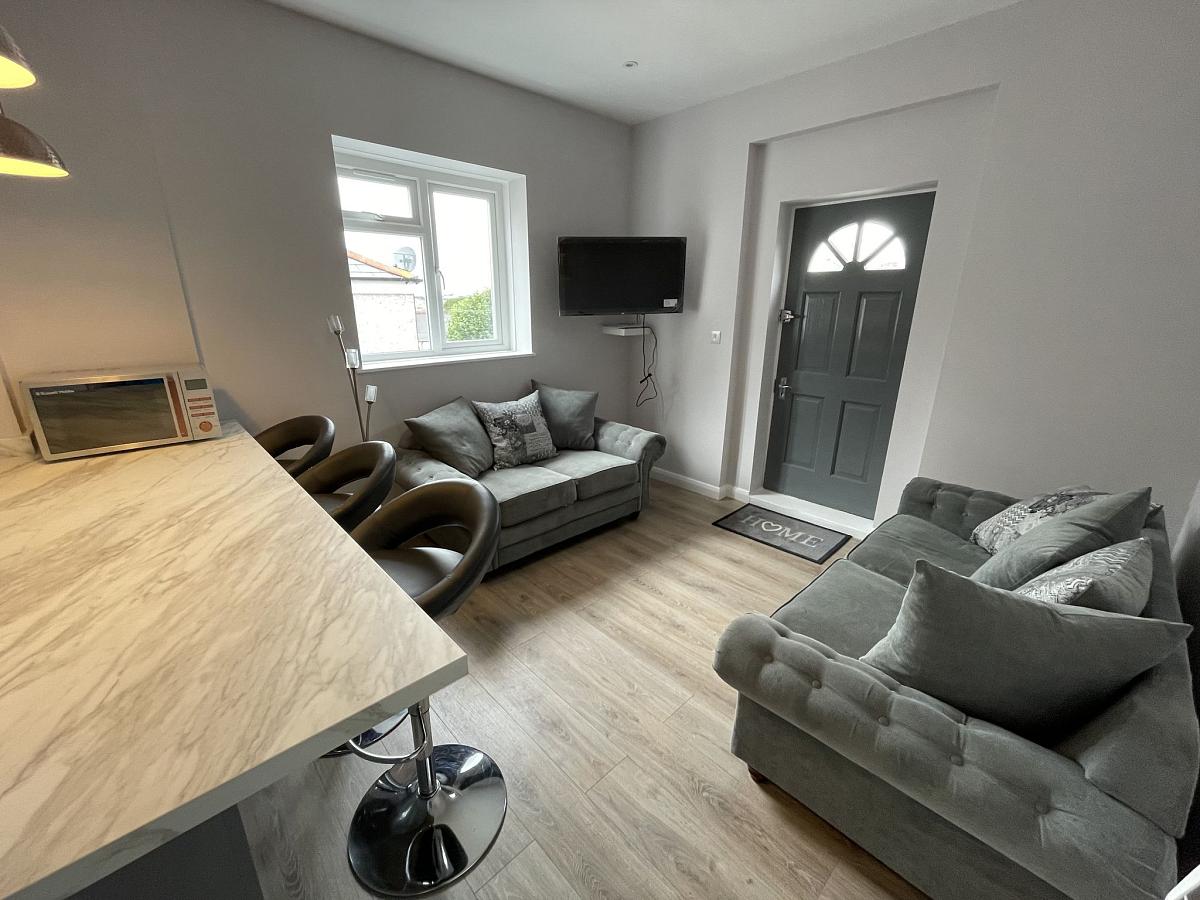 Shared living space with breakfast bar and two seater sofas
