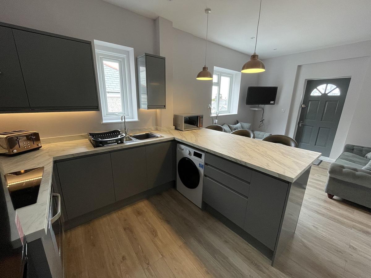 Shared kitchen with washer, breakfast bar and living area