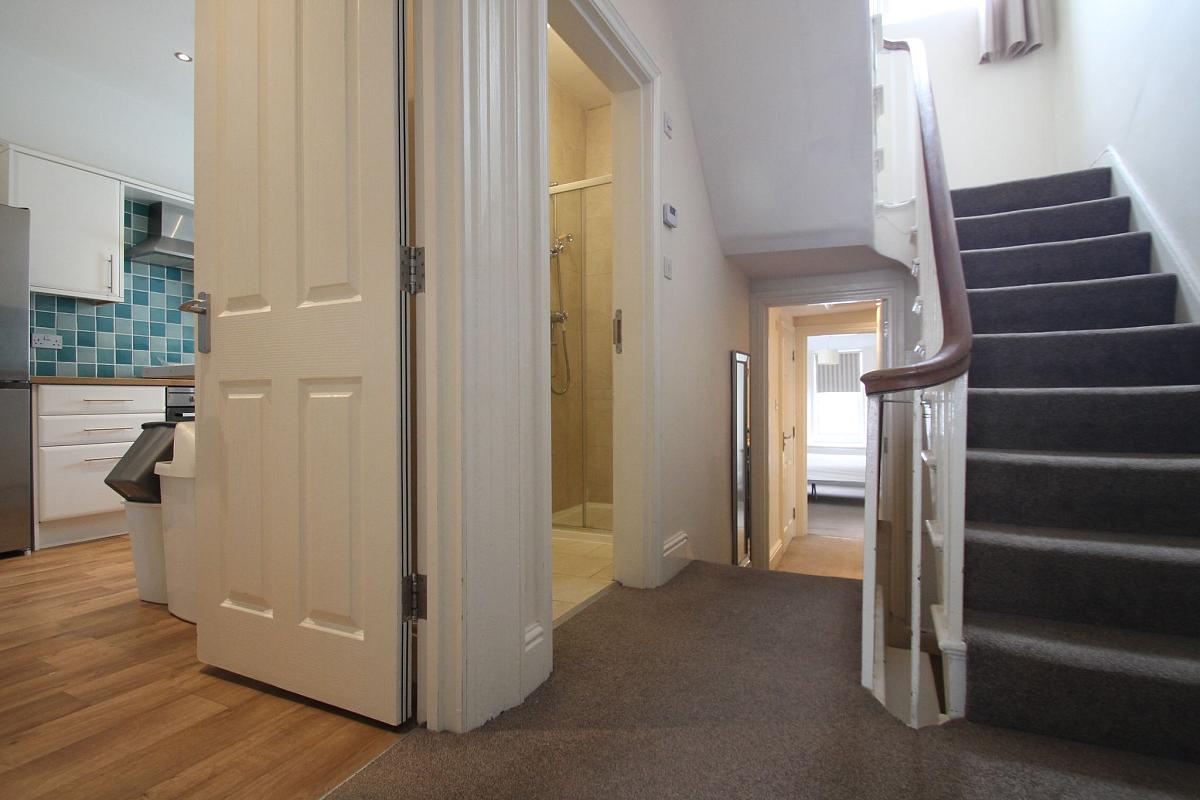 Hallway showing entrance to kitchen, shared bathroom, and upstairs