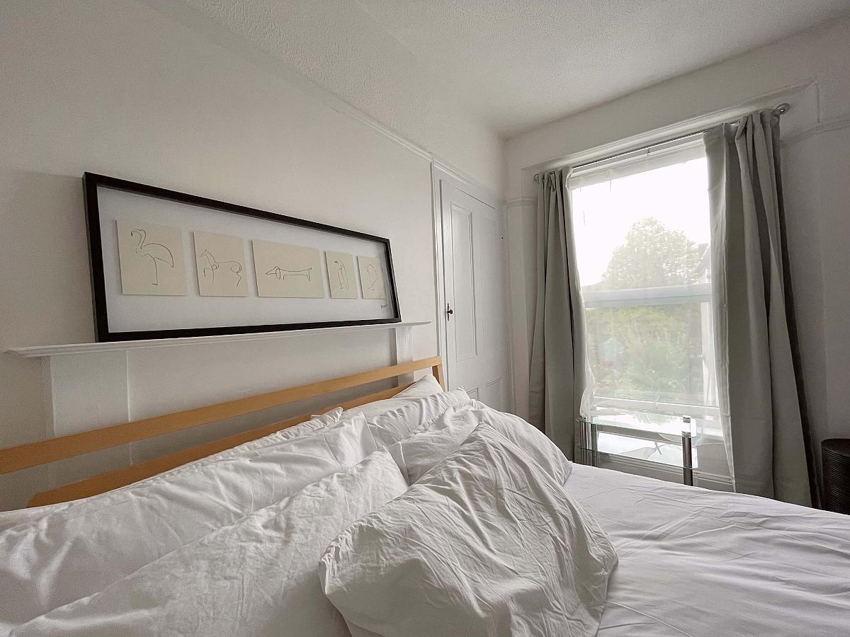 Closer view of bedroom with double bed, built-in wardrobes and picture frame above bed