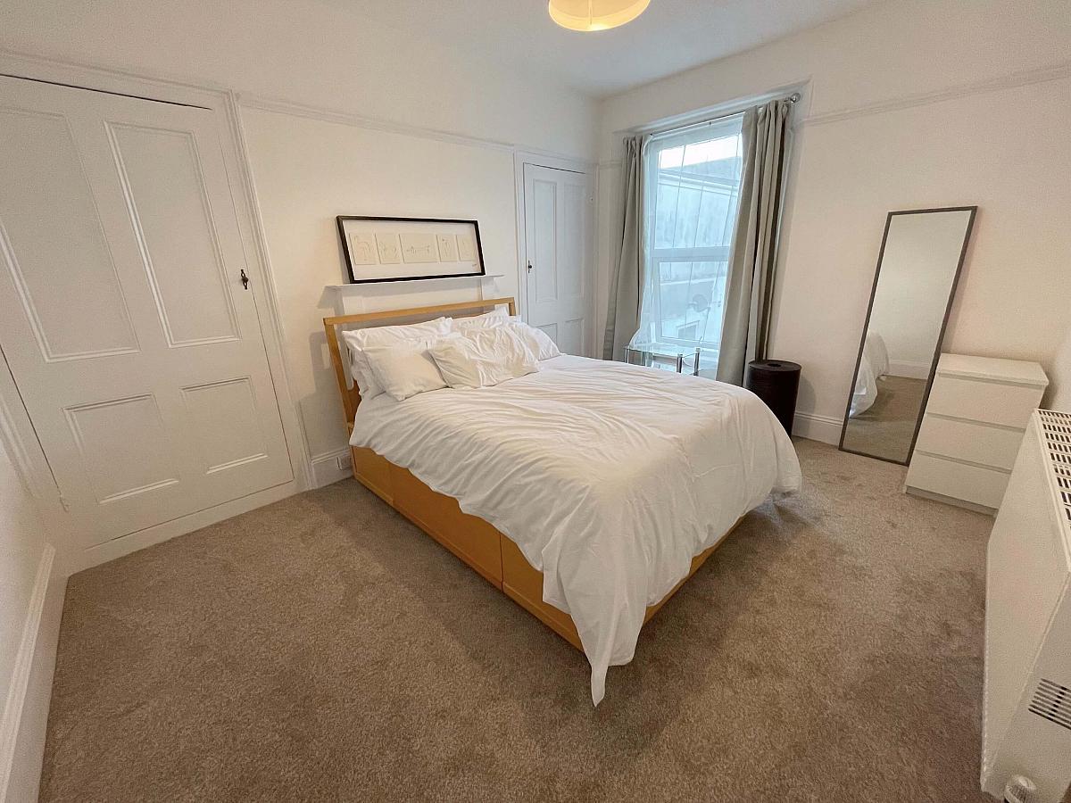 Spacious bedroom with double bed, small 3 drawer chest, two built-in wardrobes and full length mirror