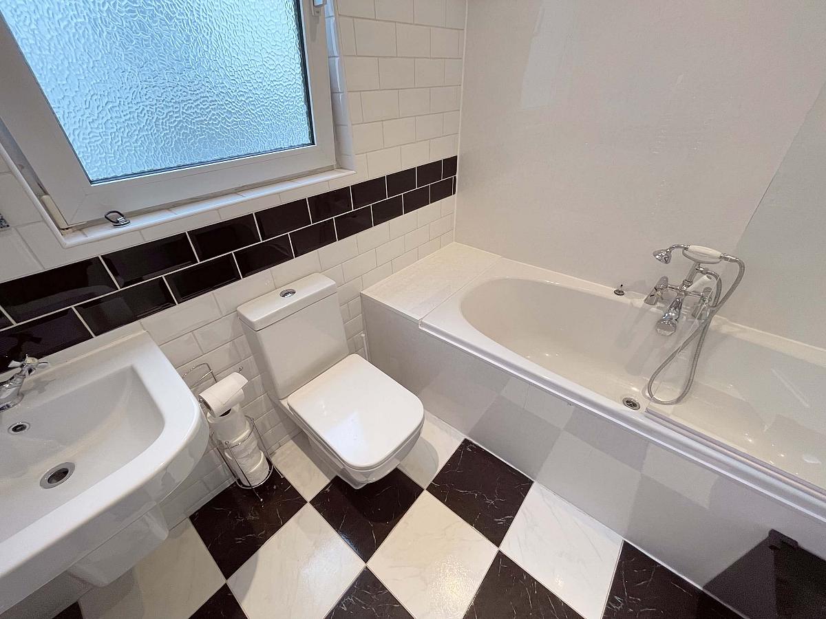White bathroom with bath with shower facility, sink and toilet