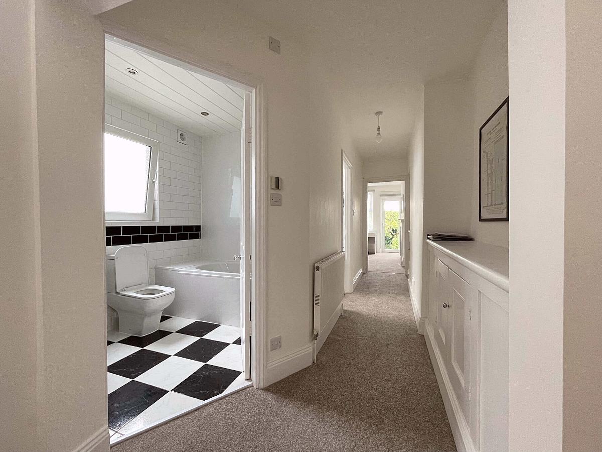 Hallway of property showing entrance to bathroom and leading into living area