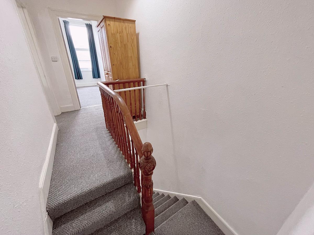 Hallway with stairs leading up to student bedroom, two door wardrobe in hallway