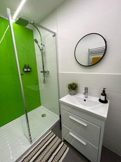 shared bathroom with large shower and sink with drawers and circular mirror above sink