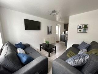 living room with two grey two-seater sofas, black coffee table and wall mounted tv
