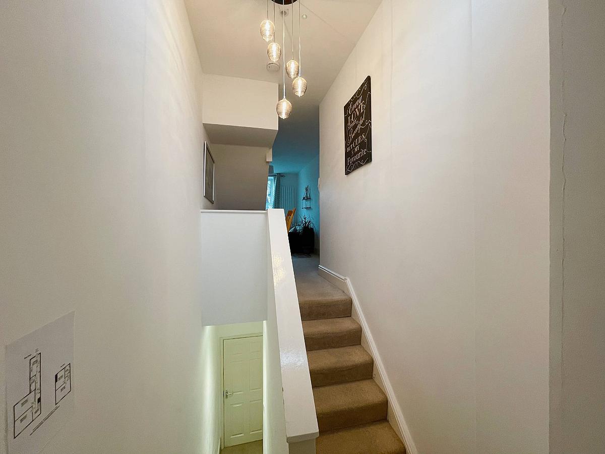 Hallway facing flat front door and stairs going towards the living area