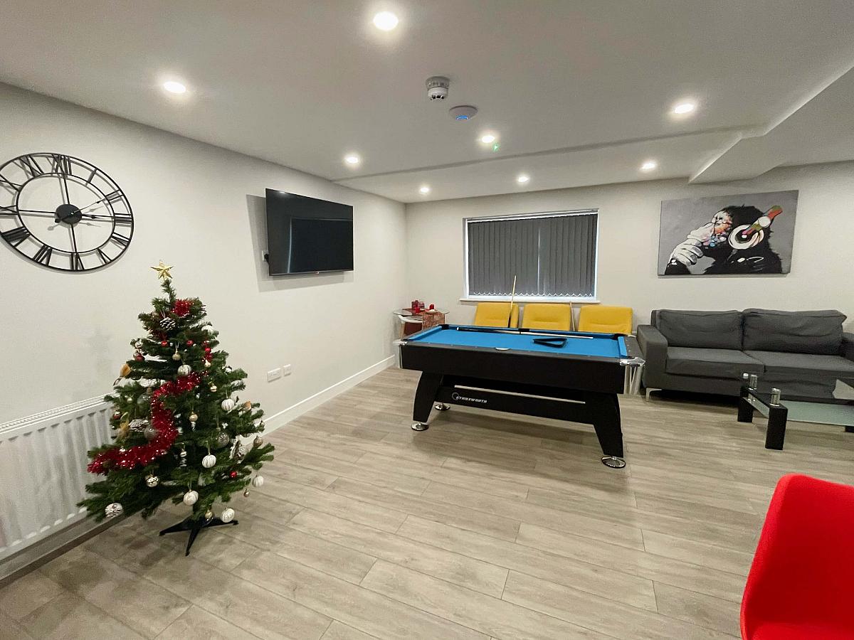 Downstairs communal area with pool table, wall mounted tv, two double seater sofas