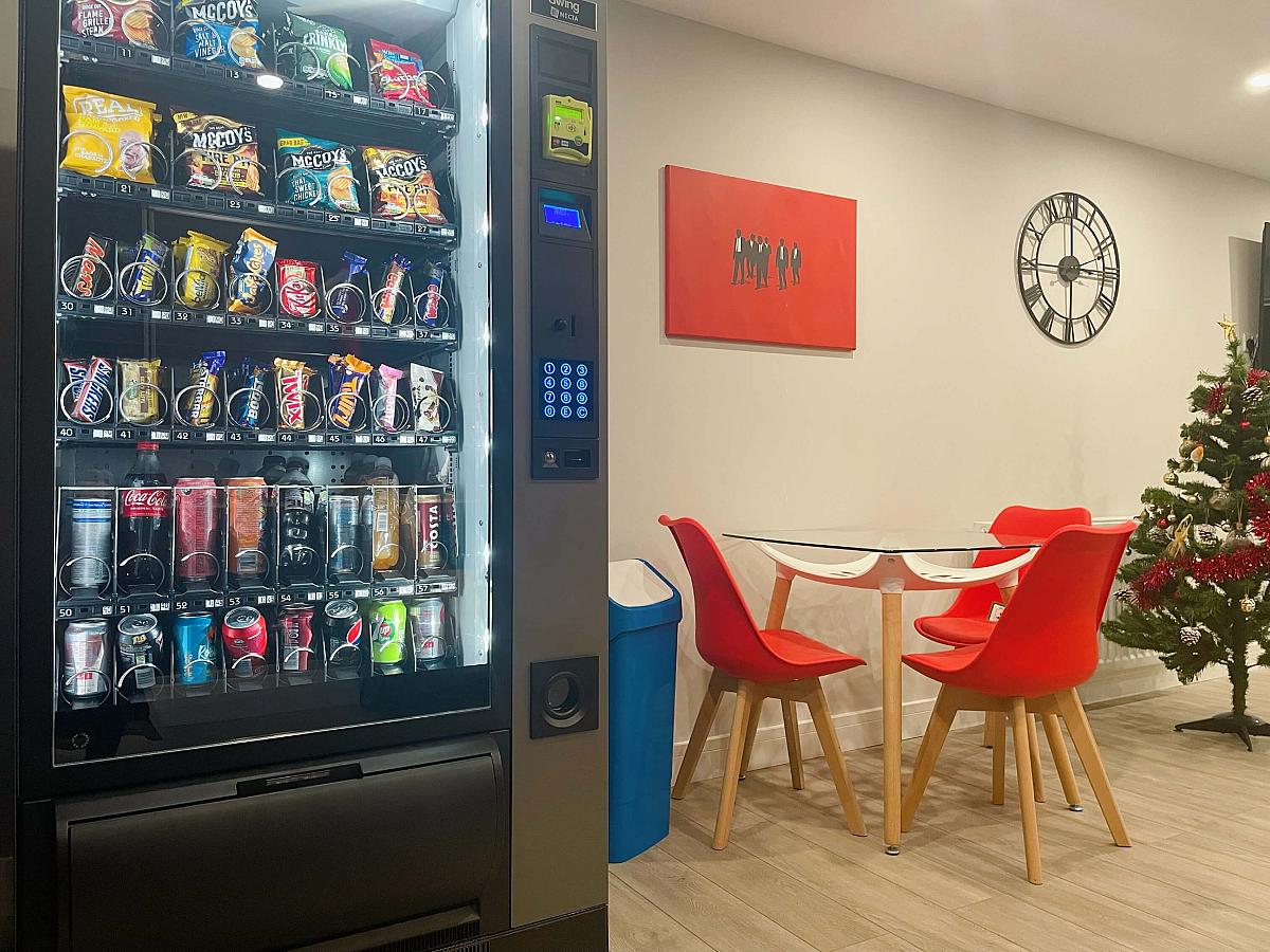 Downstairs communal area with seating of three chairs and vending machine