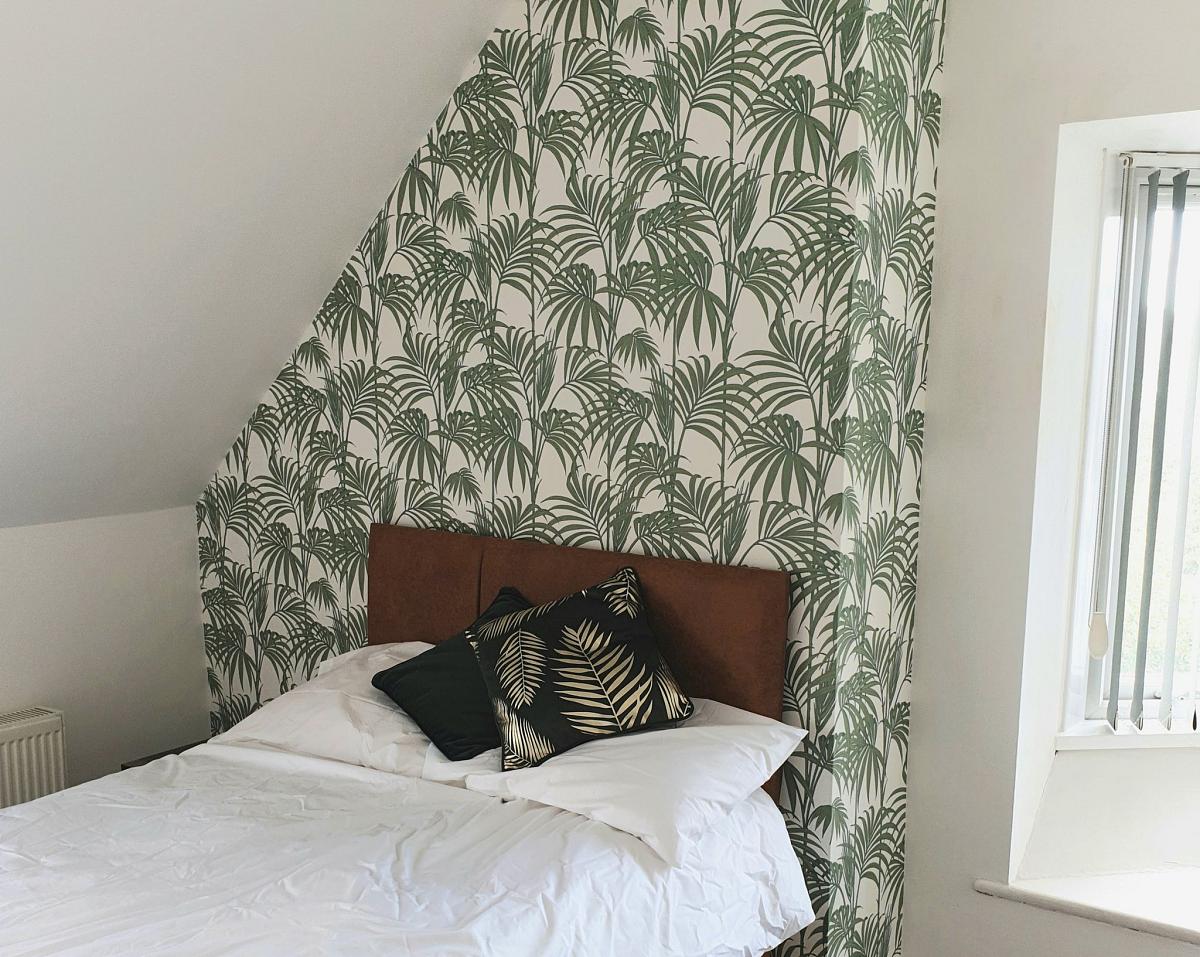 First student bedroom with double bed, wallpapered feature wall and bedside table