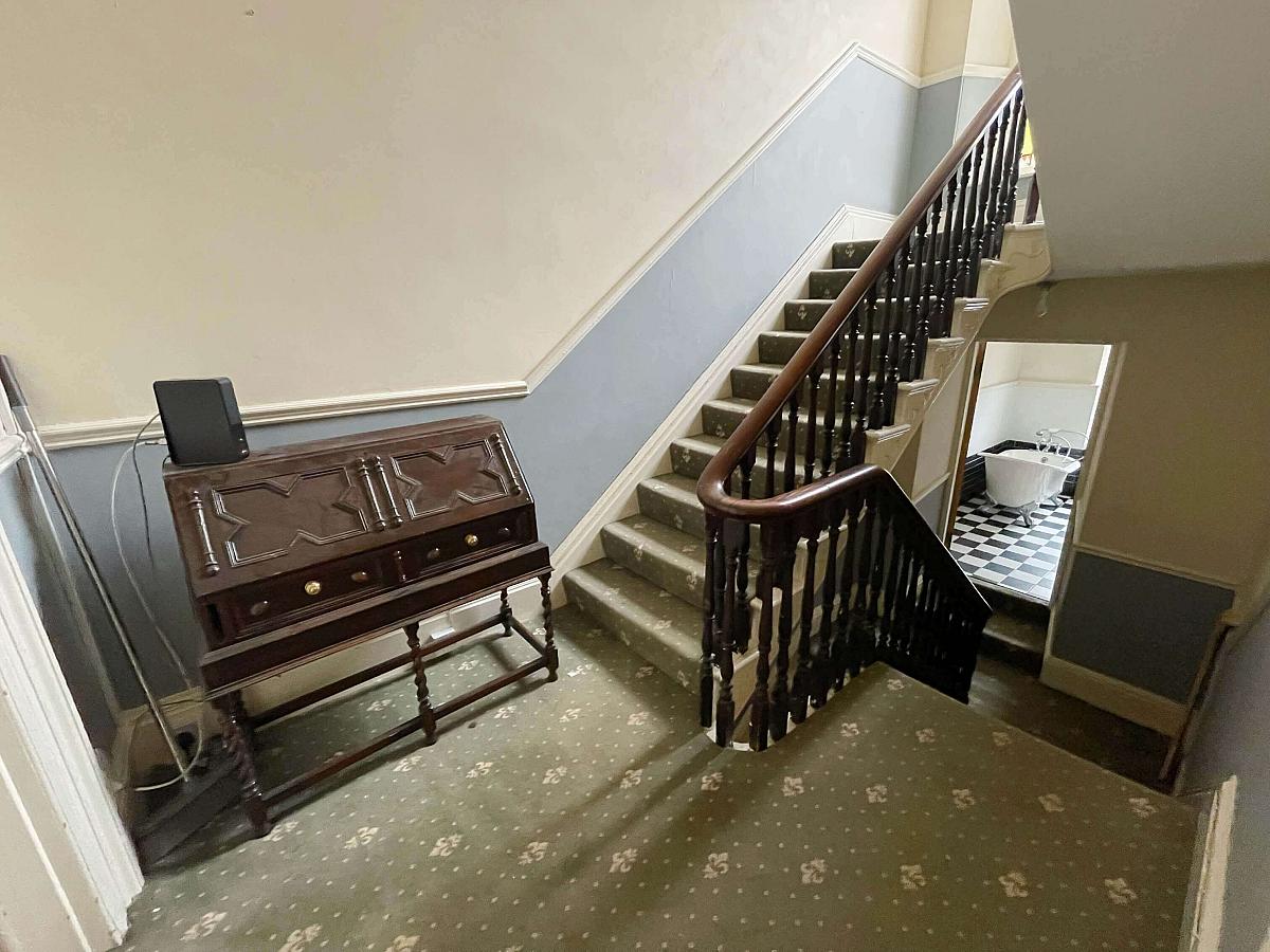 Hallway and stairs leading upstairs and into shared bathroom