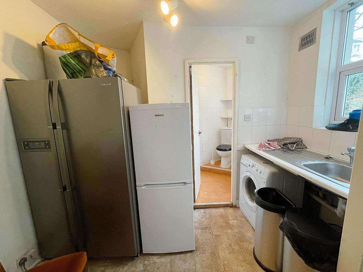Shared utility area with large double door fridge freezer, one door fridge freezer, washer dryer leading into shared WC