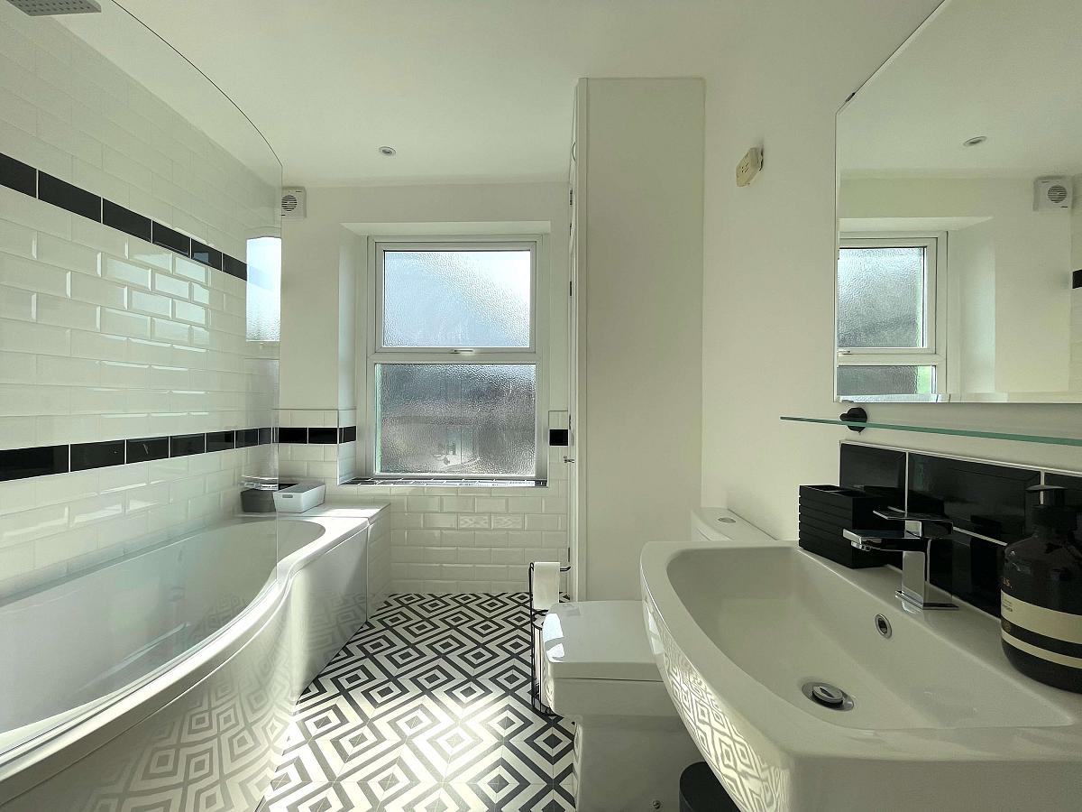 white shared bathroom with large bath with shower head plus washing machine