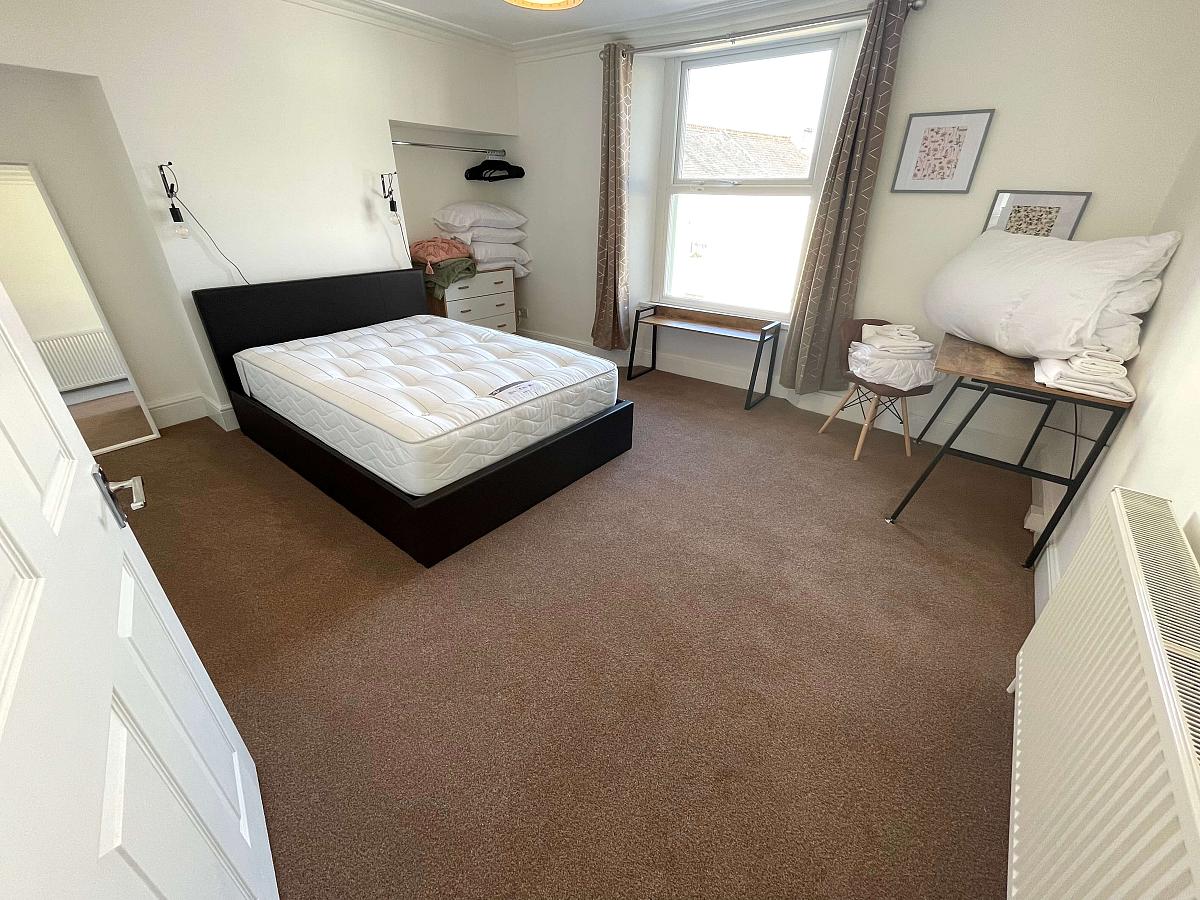 large double bedroom with desk, wardrobe and chest of drawers
