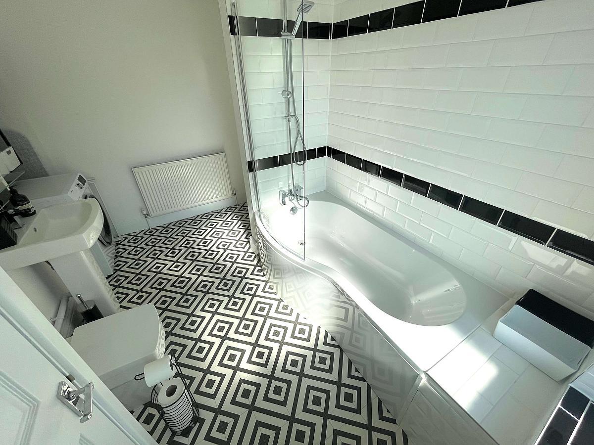 white shared bathroom with large bath with shower head