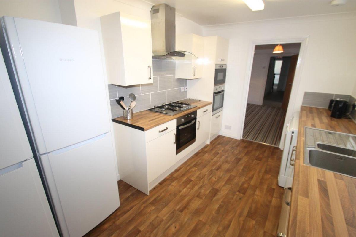 shared kitchen with gas cooker, two ovens, fridge freezers leading into living room