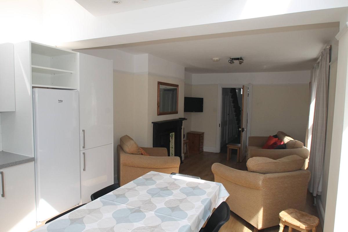open plan kitchen to living area with two-seater sofa, two armchairs, 
